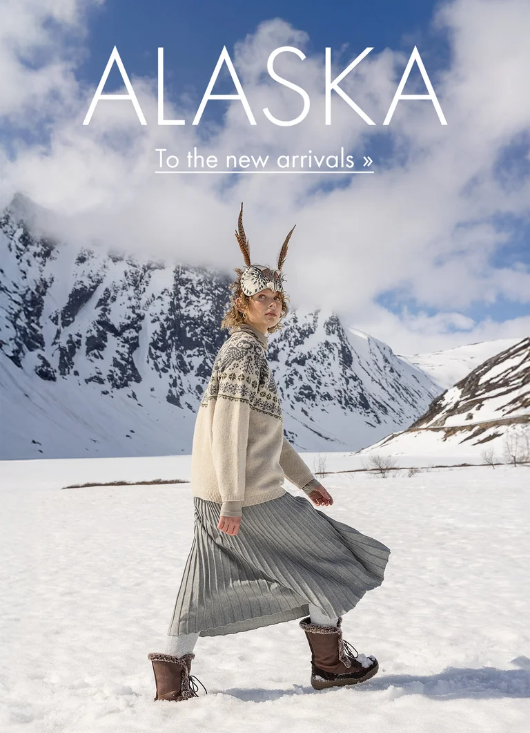 A woman walking in a snowy landscape with an animal mask on her head wearing clothes from Gudrun Sjödén’s 2025 Christmas collection. In image: Alaska