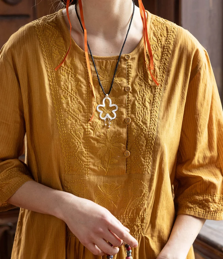 A woman wearing an embroidered yellow dress from Gudrun Sjödén. 