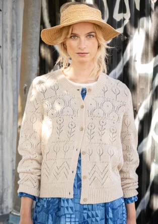 Langarmstrickjacke mit Pointelle-Stricktechnik in der Farbe hellsand. Komibiniert mit einem blaugemusterten Webkleid. 