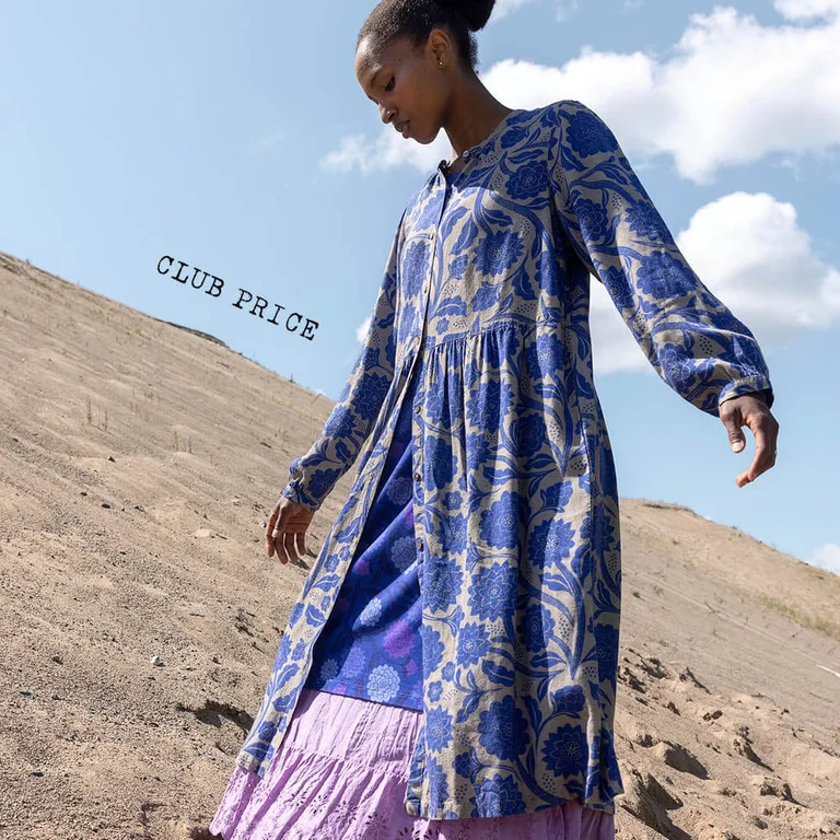 A woman wearing a floral blue shirt dress from Gudrun Sjödén.