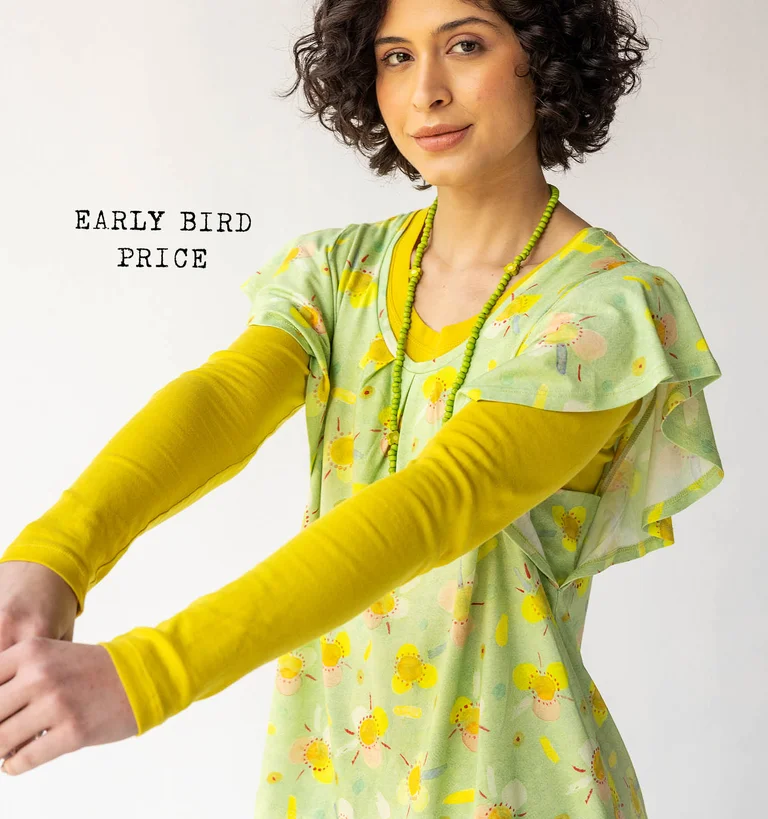 A woman dressed in a patterned green jersey-fabric top, worn over a yellow long-sleeved top from Gudrun Sjödén.
