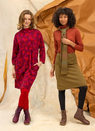 A woman wearing a colourful block-pattern cardigan from Gudrun Sjödén. Img alt-text: Two women next to each other wearing essentials from Gudrun Sjödén’s 2026 Autumn collection.