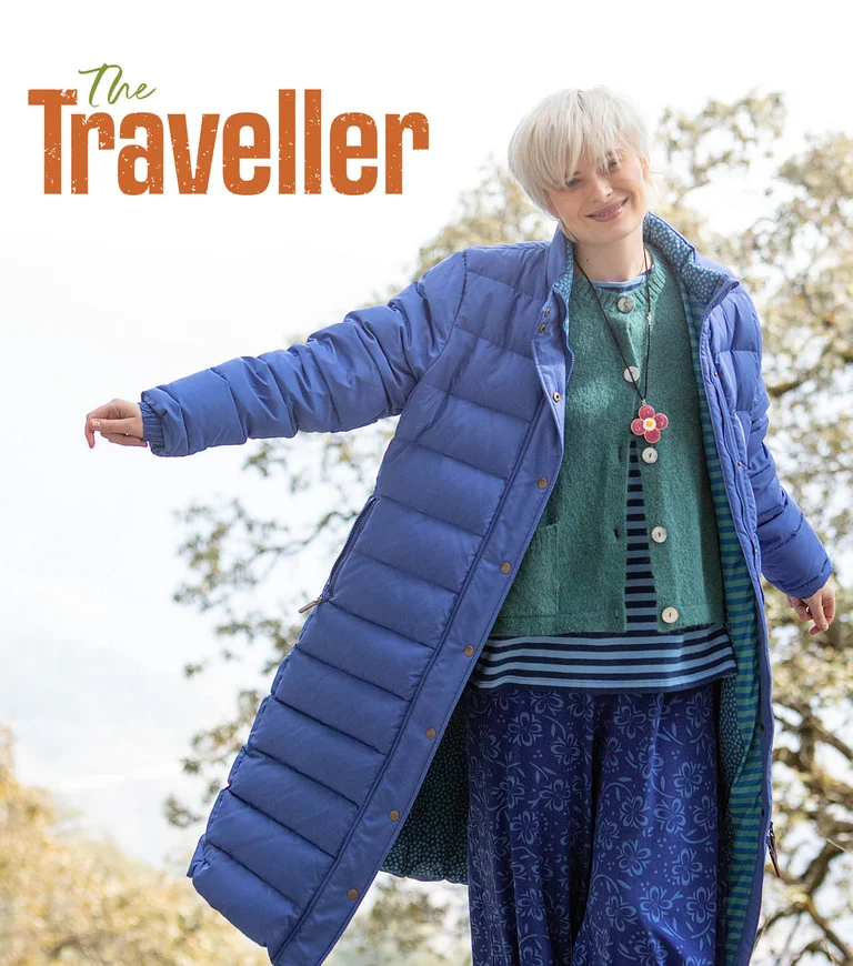 A woman wearing a long blue down coat from Gudrun Sjödén, over layers of clothing from Gudrun Sjödén.