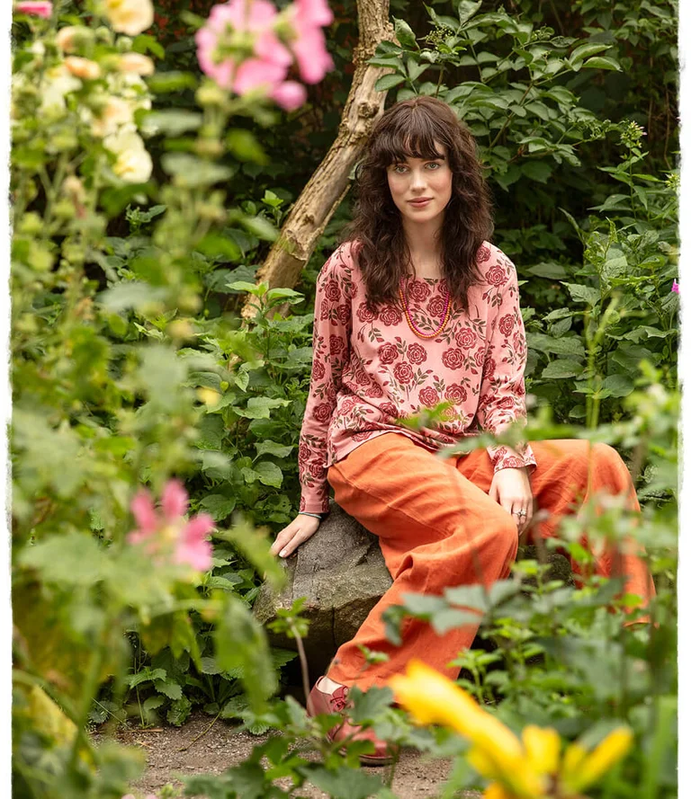 A woman wearing a rose-patterned top and orange trousers from Gudrun Sjödén.