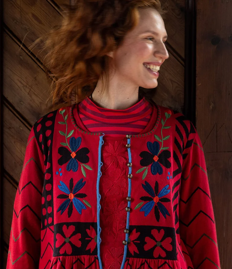 A woman wearing a red embroidered cardigan from Gudrun Sjödén.  