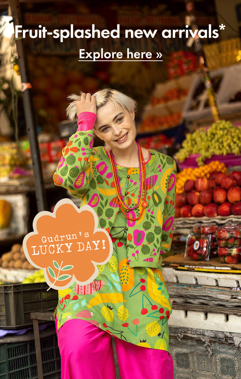 A collage of a woman standing with lots of fruit, wearing clothes from Gudrun Sjödén printed with brightly-coloured fruit patterns.