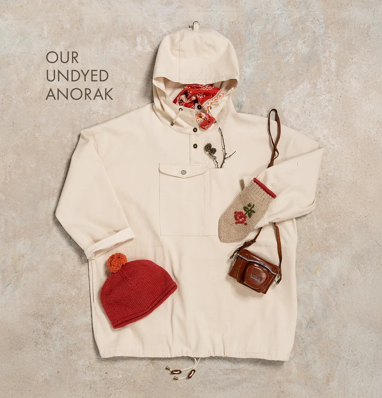 A flat-lay photo of a white anorak and matching accessories from Gudrun Sjödén.