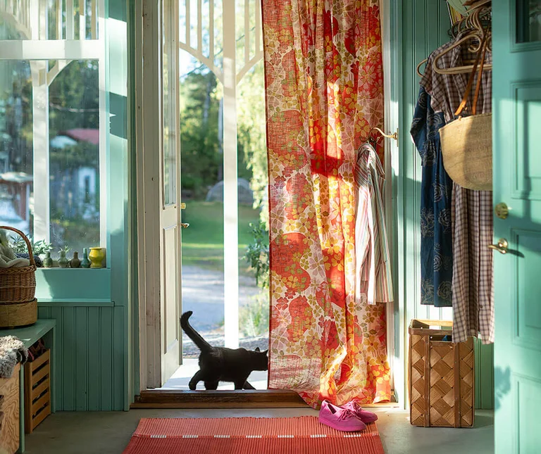 An open door with an orange patterned curtain from Gudrun Sjödén.