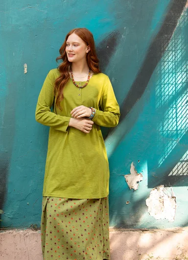 A woman wearing layers of clothes in shades of green from Gudrun Sjödén.