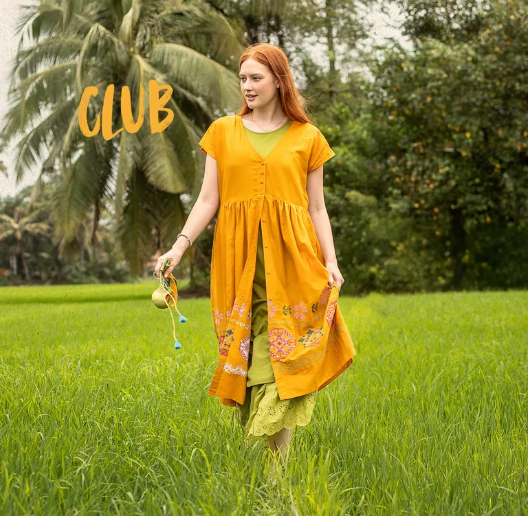A woman wearing a yellow, embroidered dress from Gudrun Sjödén.
