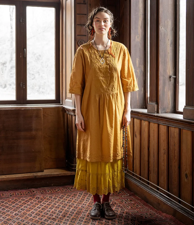 A woman wearing a yellow dress and skirt from Gudrun Sjödén.  