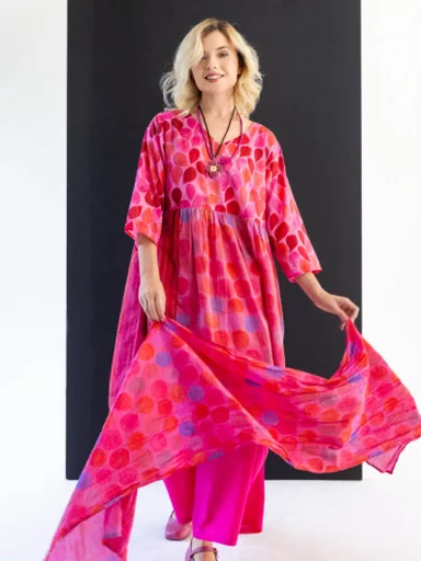 A woman wearing a pink-red patterned dress from Gudrun Sjödén.