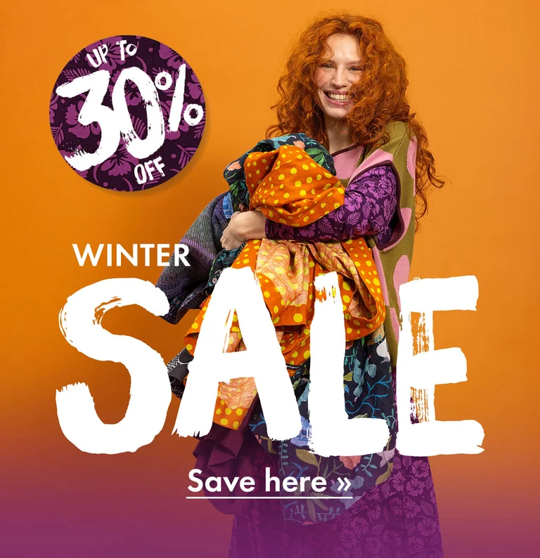 A woman with her arms full of colourful clothes from Gudrun Sjödén.