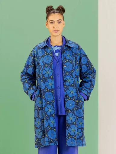 A woman wearing a knitted waistcoat over a patterned dress from Gudrun Sjödén.