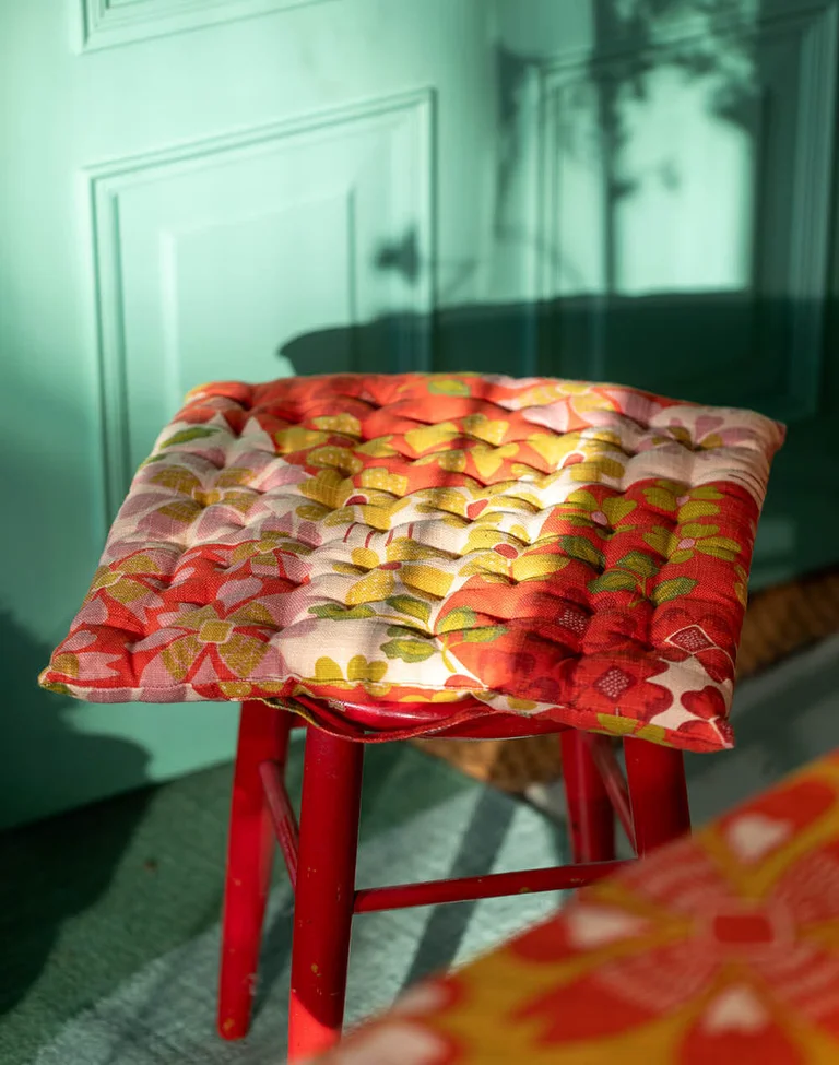 A patterned seat cushion from Gudrun Sjödén on a red stool.