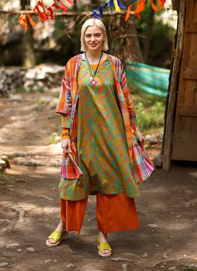 An upper body wearing layers of patterned clothes from Gudrun Sjödén.