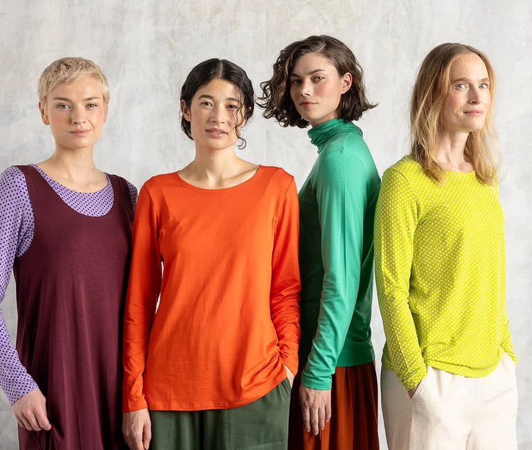 Four women standing close together dressed in colourful jersey tops from Gudrun Sjödén.