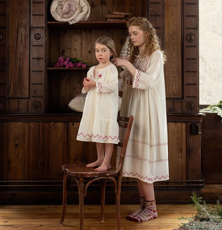 A woman and a girl wearing embroidered nightgowns from Gudrun Sjödén. 