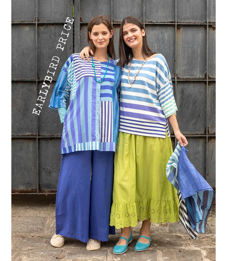 Two women wearing striped clothes from Gudrun Sjödén. One woman is holding a matching scarf in her hand.