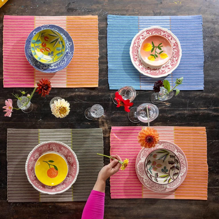 Une table avec des sets de tables de différentes couleurs signés Gudrun Sjödén.