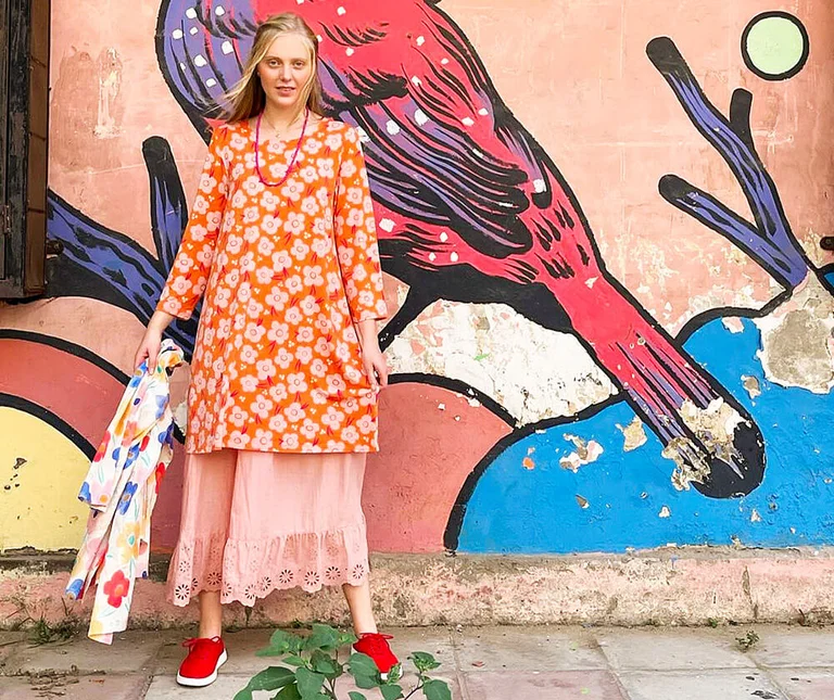 A woman wearing a floral dress from Gudrun Sjödén with street art in the background 