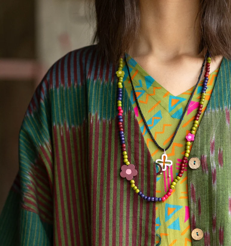 A close-up of a woman’s neck with two necklaces from Gudrun Sjödén.