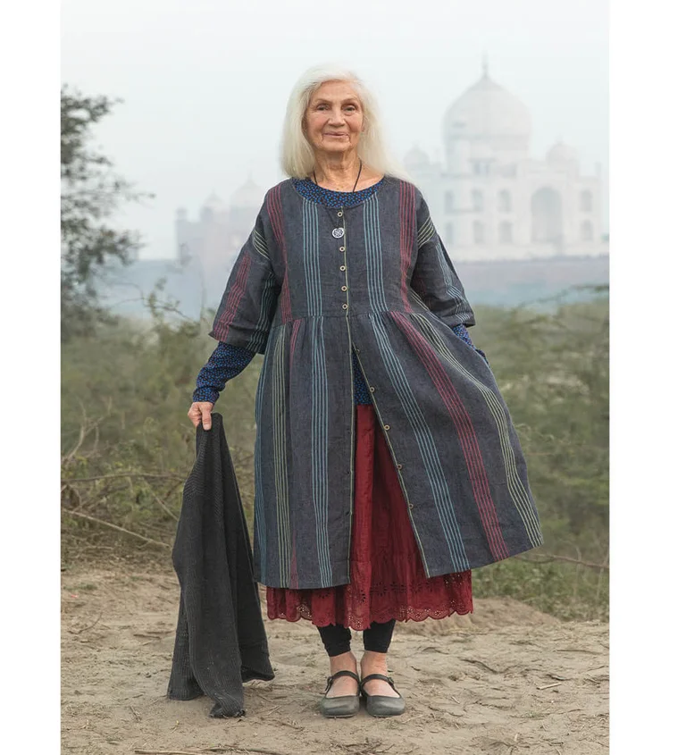 A woman outdoors wearing a woven dress with buttons from Gudrun Sjödén.