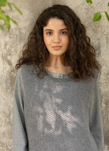 A woman wearing layers of clothes in shades of green from Gudrun Sjödén.