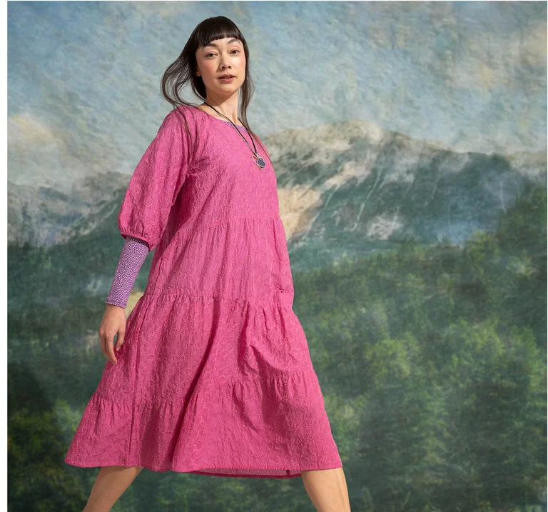 A woman in motion wearing a pink dress from Gudrun Sjödén.