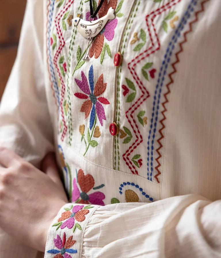 A woman wearing an embroidered white tunic from Gudrun Sjödén. 