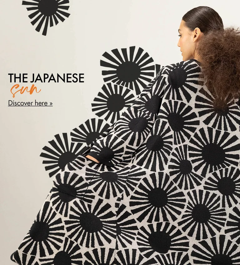 A woman with her back to the camera, wearing a long cardigan with a pattern of black, geometric suns from Gudrun Sjödén. The pattern has been extended in the image so it looks like it is flowing out from the cardigan.