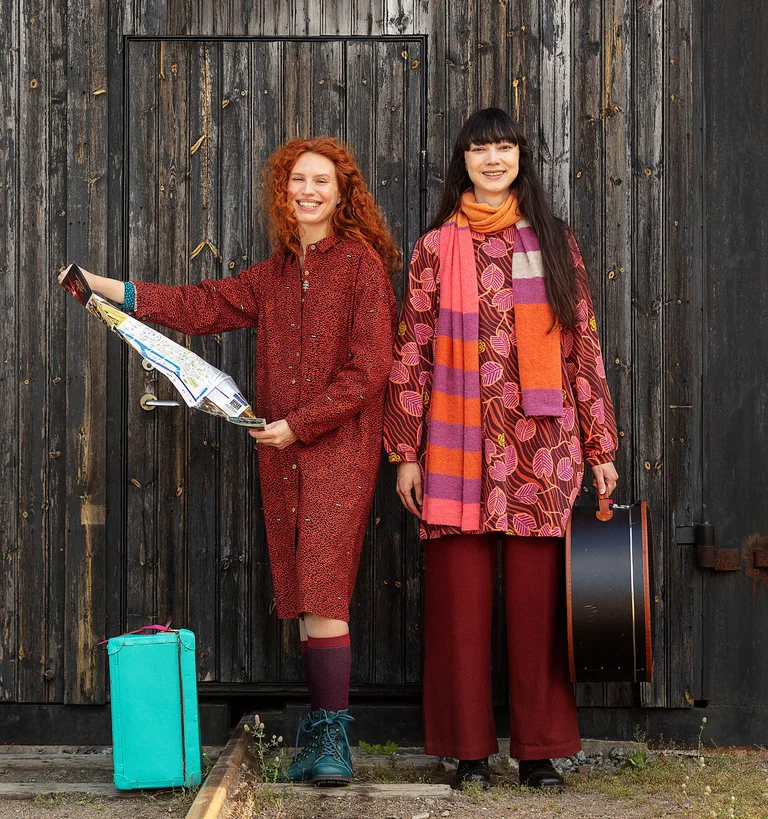 Two women next to each other reading a map wearing clothes from Gudrun Sjödén.