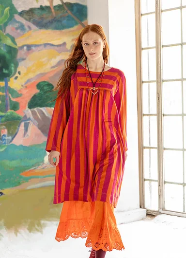 A woman wearing a brown blouse over a striped dress from Gudrun Sjödén.