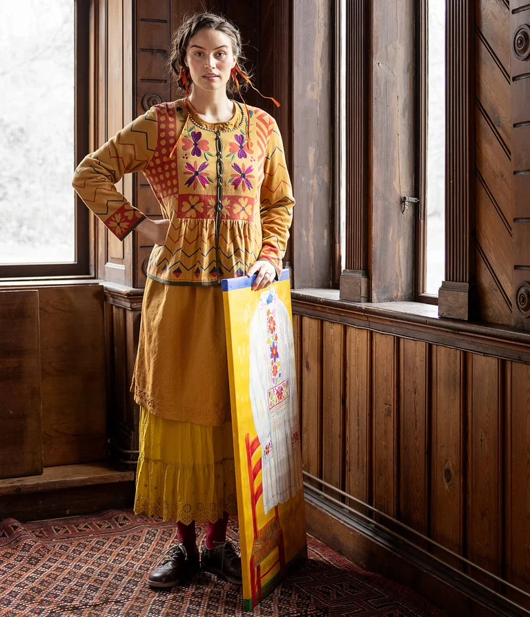 A woman wearing a yellow cardigan and skirt from Gudrun Sjödén.  