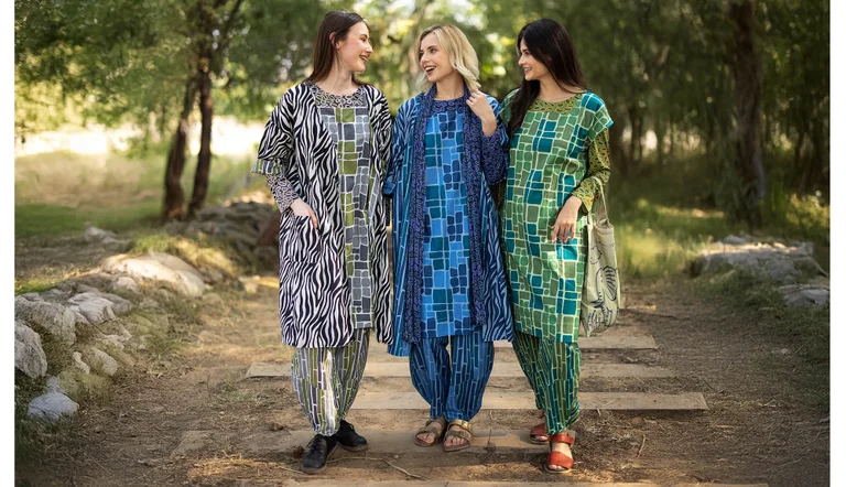Three women standing next to each other outdoors wearing patterned clothes from Gudrun Sjödén.
