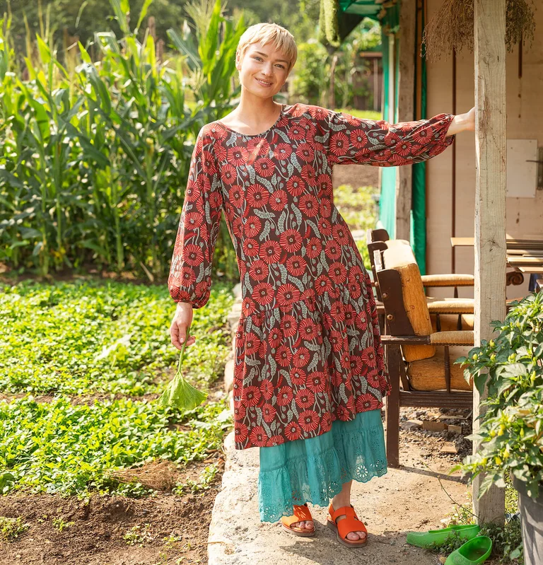 En kvinna klädd i en klänning med blommönster från Gudrun Sjödén. 