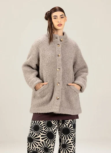 A woman wearing a fluffy, beige jacket from Gudrun Sjödén.