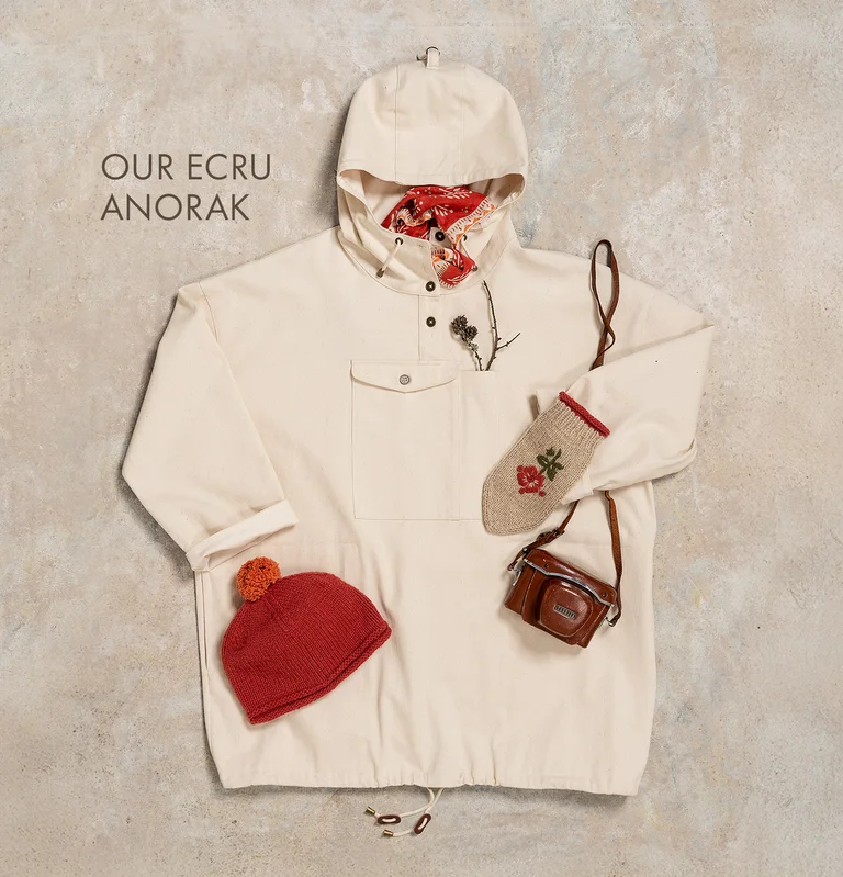 A flat-lay photo of a white anorak and matching accessories from Gudrun Sjödén.