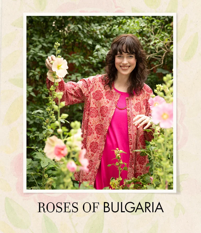 A woman wearing a pink dress and rose-patterned tunic from Gudrun Sjödén.