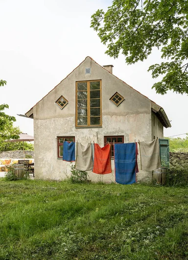 Home textiles from Gudrun Sjödén hanging on a clothesline in front of a house.