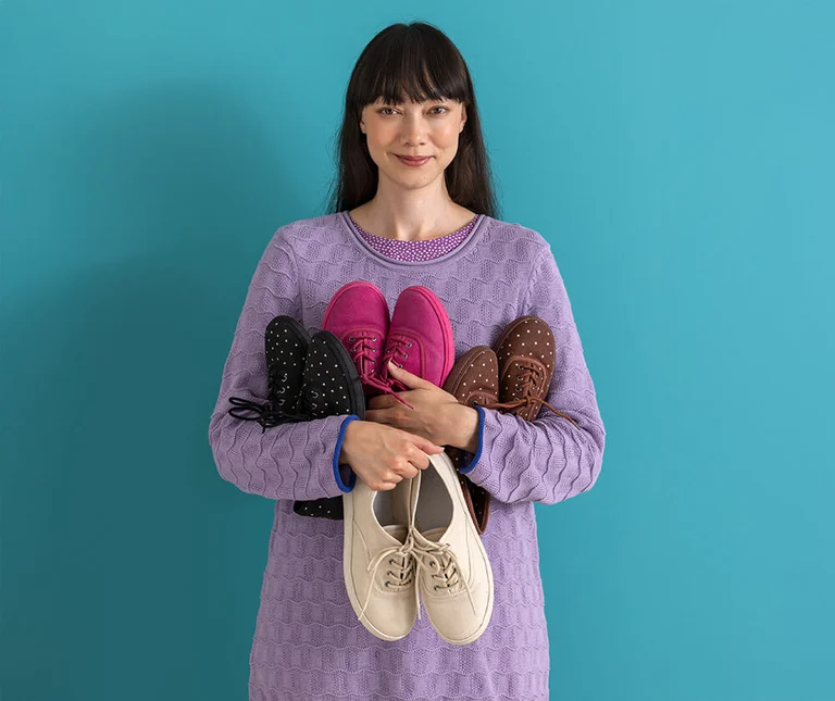 A woman with an armful of shoes from Gudrun Sjödén.