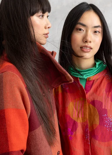 A seated woman wearing turquoise corduroy clothes from Gudrun Sjödén.