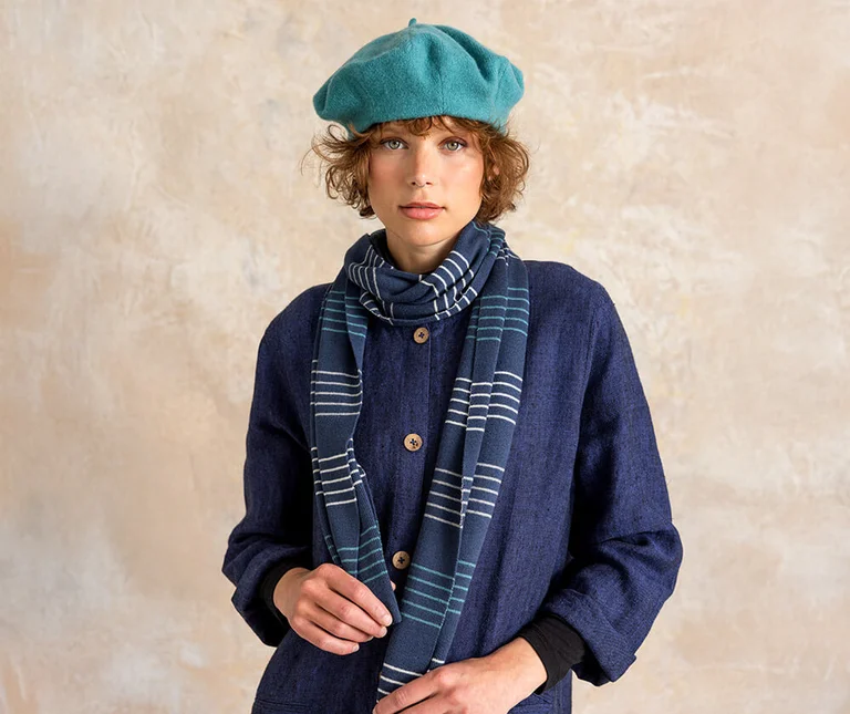 A woman wearing a beret and a large knit scarf from Gudrun Sjödén.